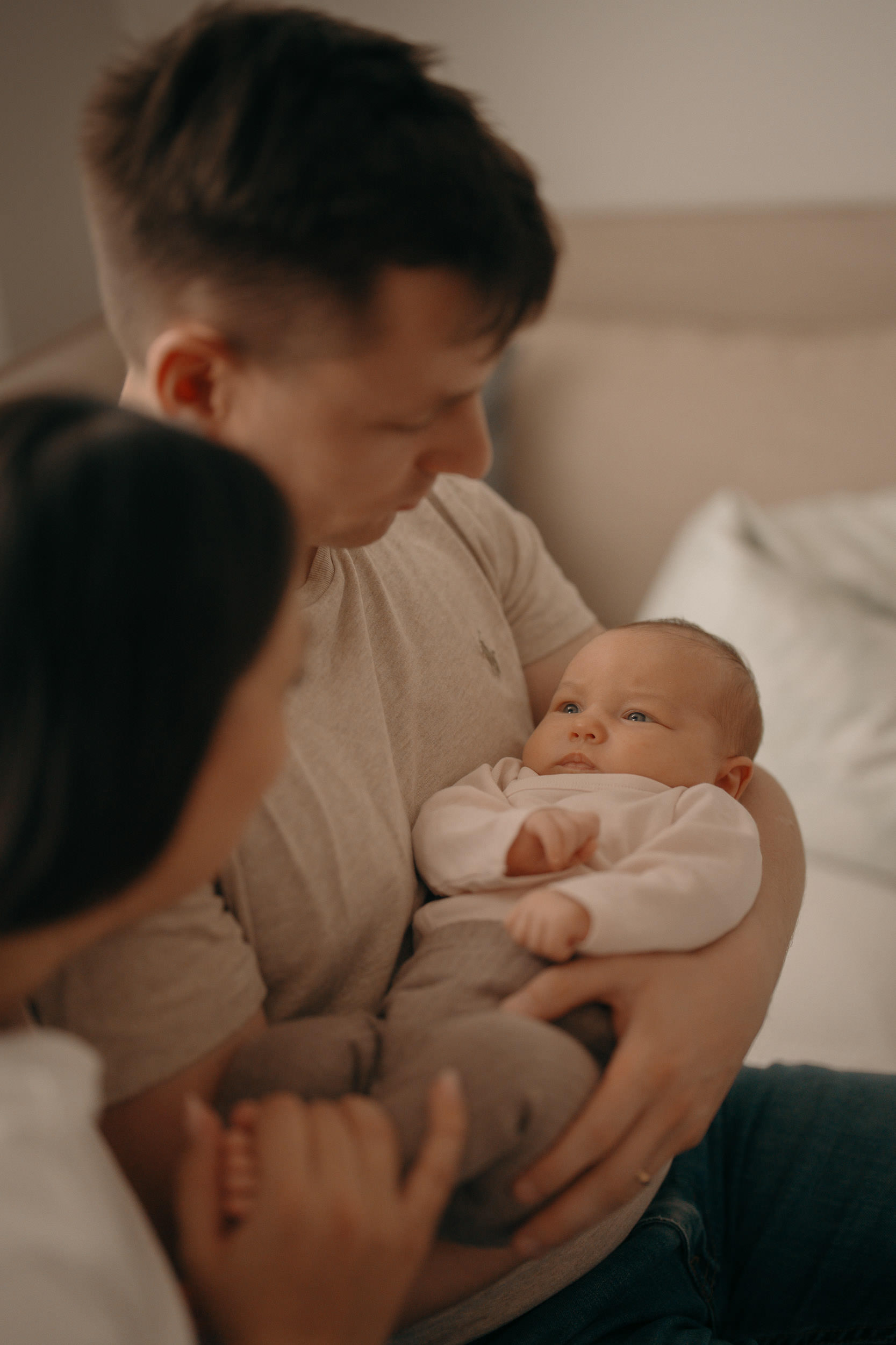 Newborn Shooting zuhause – Eltern halten ihr Neugeborenes liebevoll im Arm